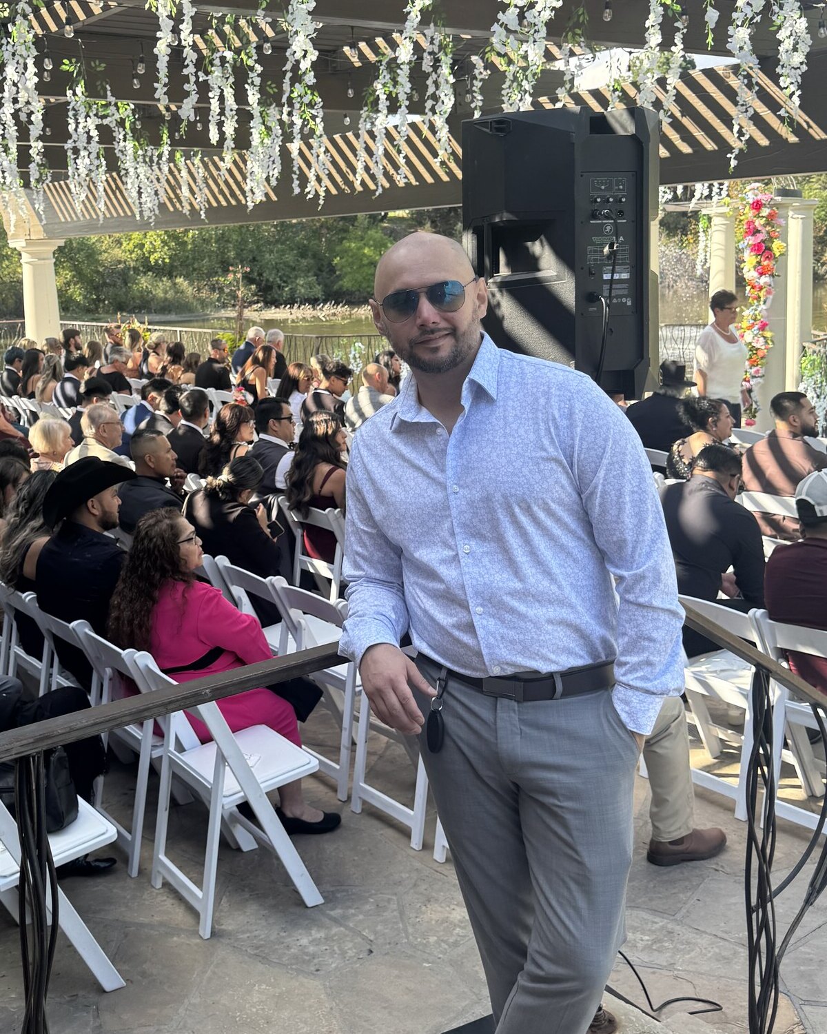 Jimmy Yar standing at an outdoor wedding ceremony, wearing sunglasses